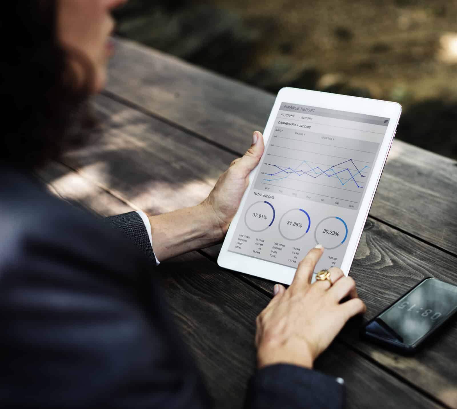 A woman holding a tablet with graphs on it.