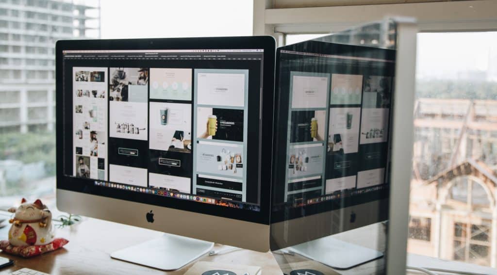 A desk with a computer screen and a monitor.