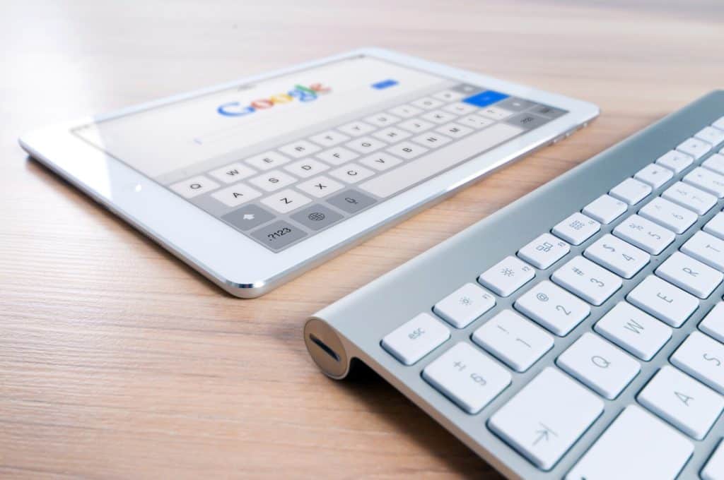A tablet computer and keyboard on a wooden table.