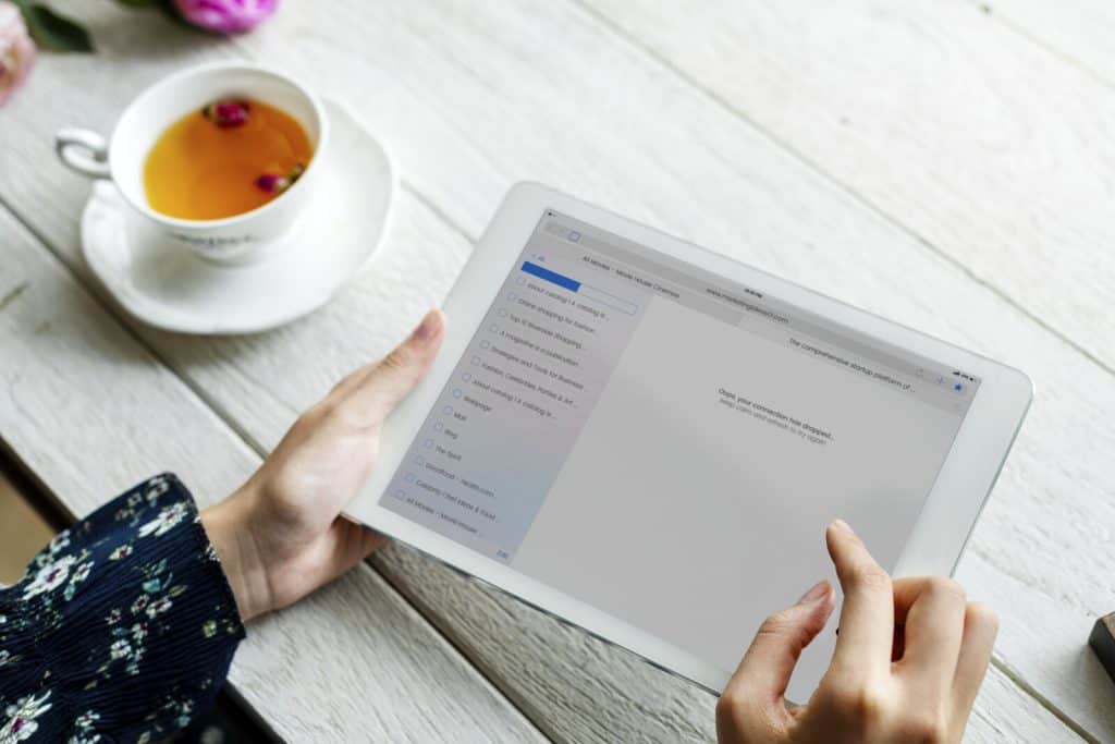 A woman holding an ipad with a cup of tea.
