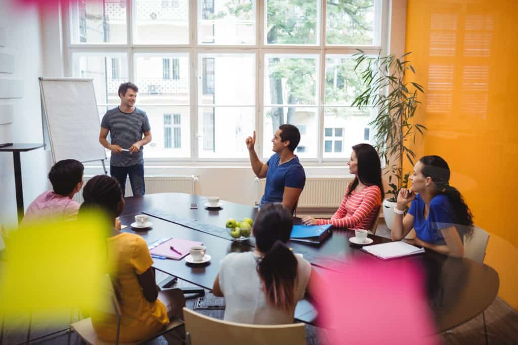 A group of people sitting around a table in a meeting room.