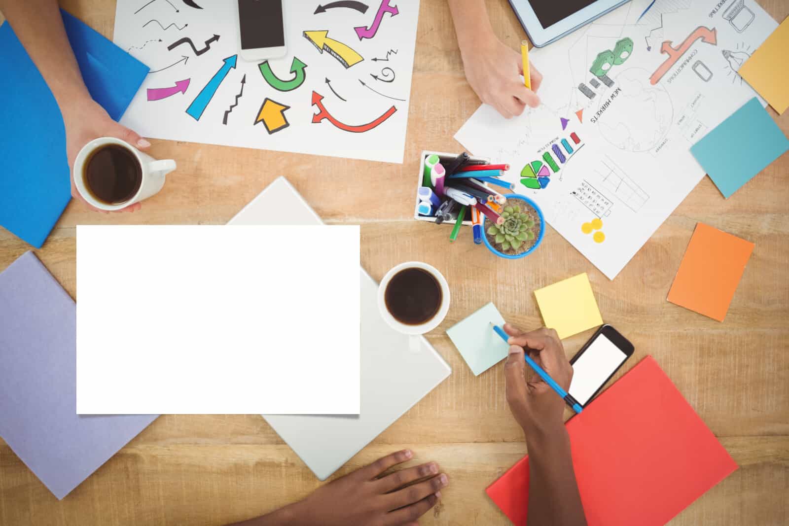 A group of people sitting around a table with a blank sheet of paper.