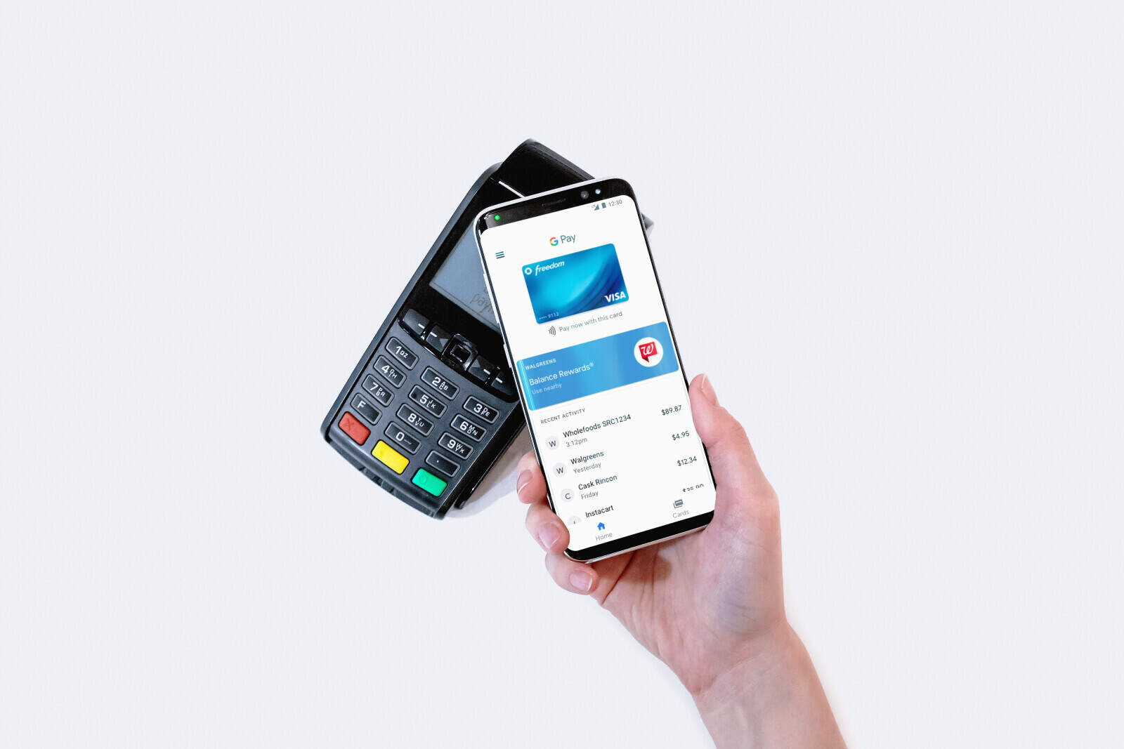 A hand holding a smartphone next to a samsung payment terminal.