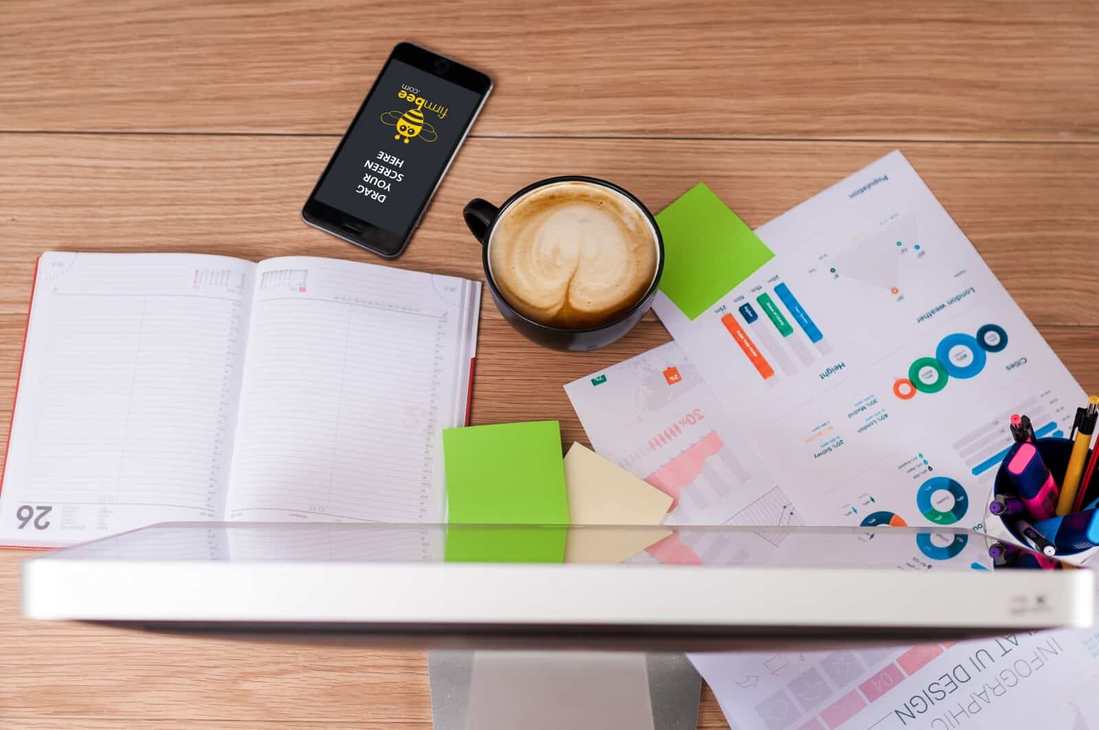A desk with a cup of coffee, a notebook and a cell phone.