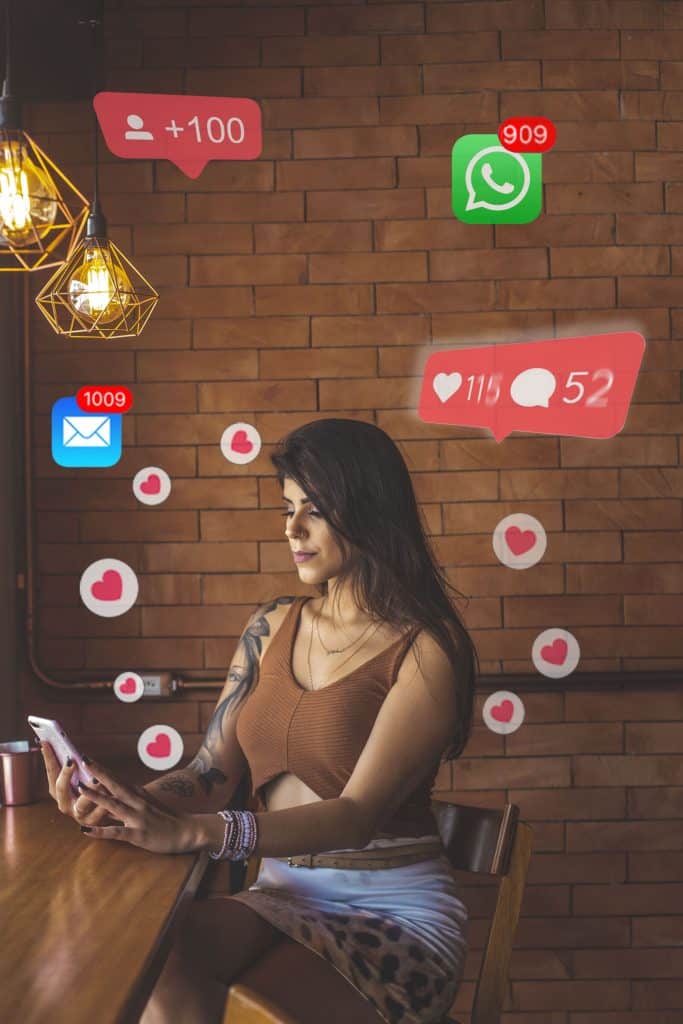 A woman sitting at a table with social media icons surrounding her.