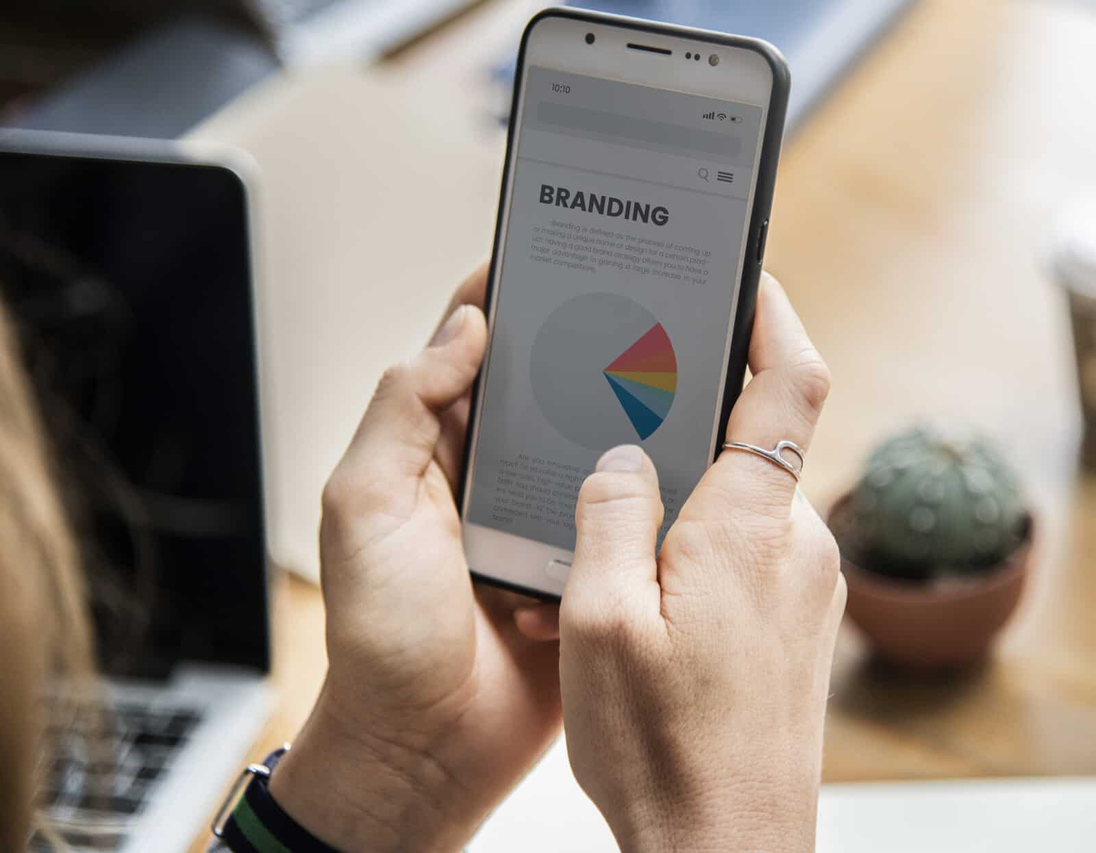 A woman holding a smartphone with a pie chart on it.
