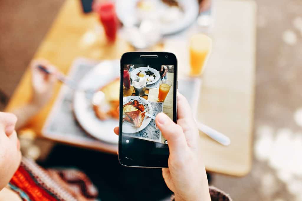 A woman taking a photo of food on her phone.