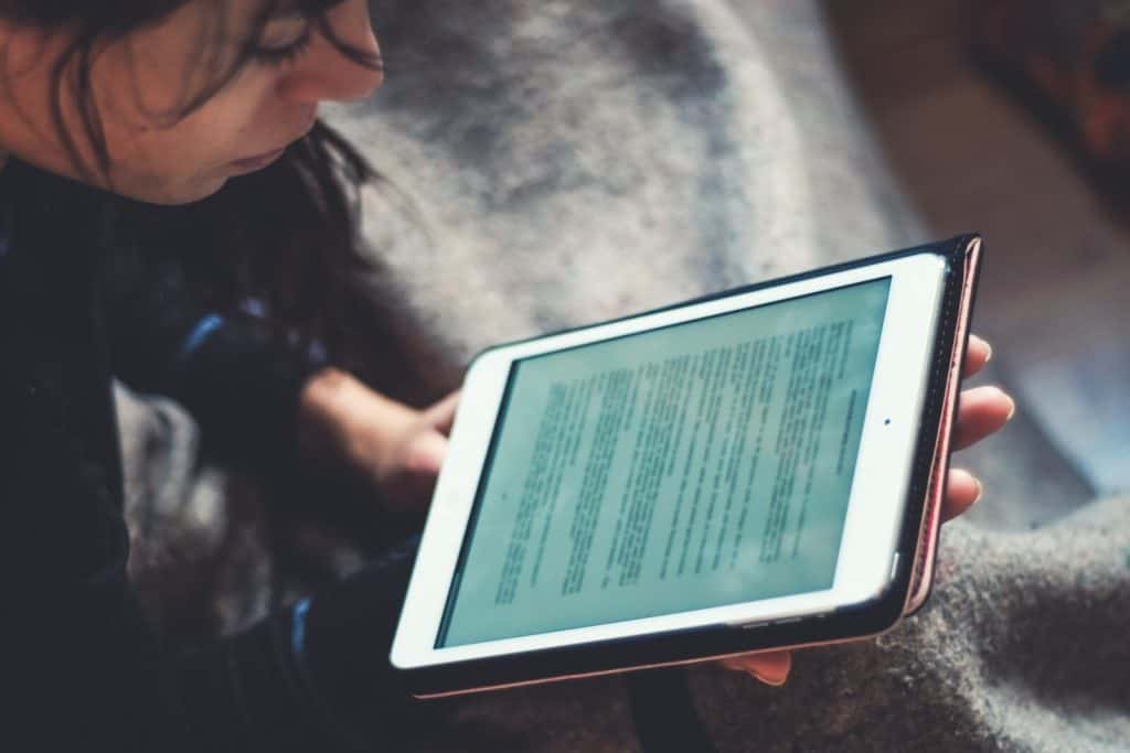 A woman reading a book on an ipad.