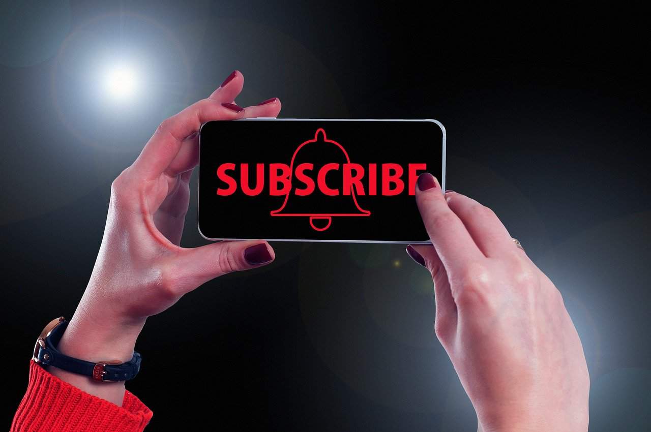 A woman takes a picture of a phone with the word subscribe on it.